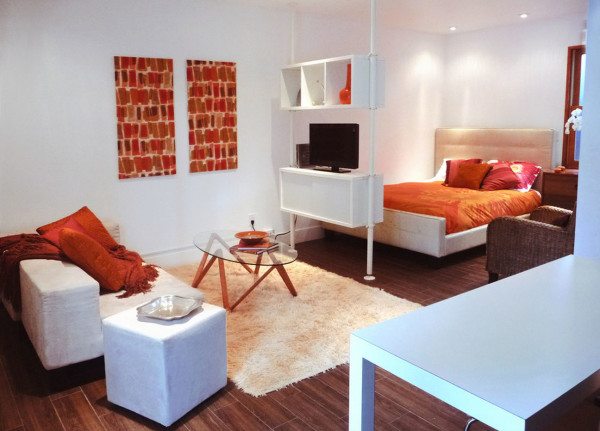 Вид спального места в комнате, разграниченной с использованием стеллажа.