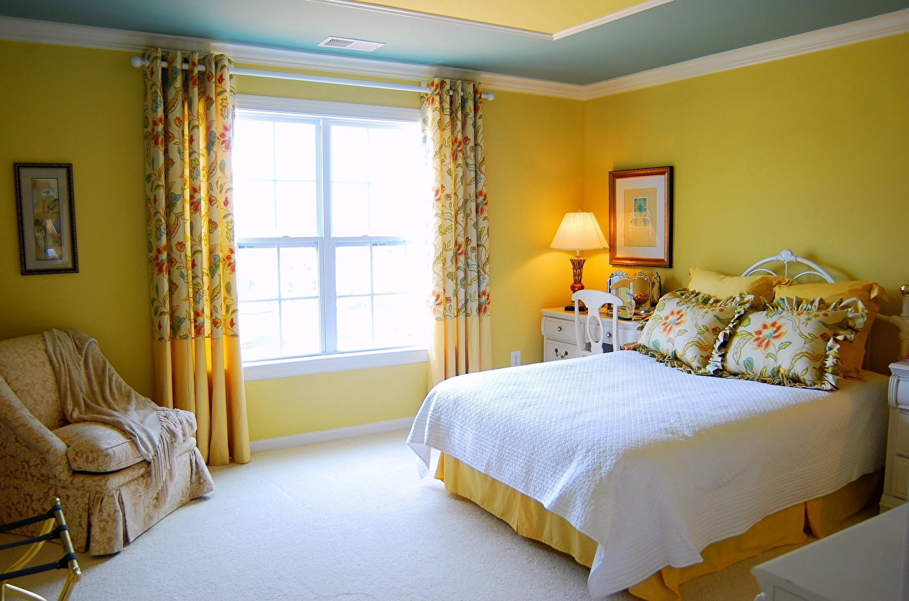 Кровать изголовьем к окну в спальне желтой
