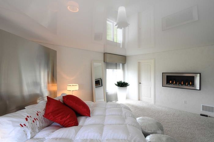 Две красные подушки на белом покрывале кровати